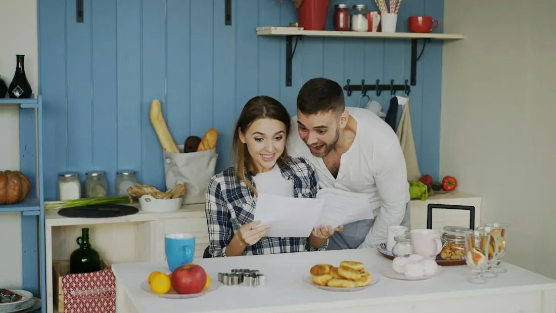Pareja revisando papeles de la reforma en la cocina de casa